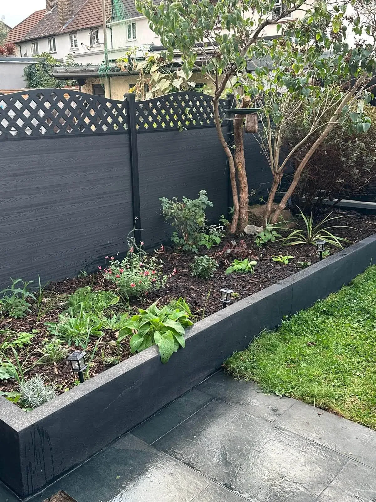 Planted black sleeper bed along a composite fence with a lattice top