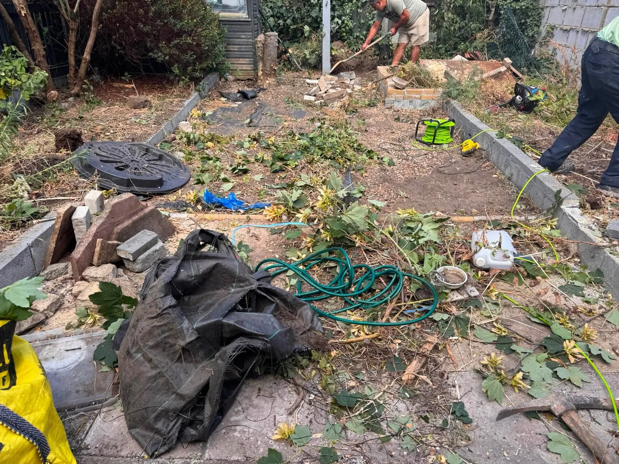 Before: the same garden overgrown, with old slabs, rubble and broken edging