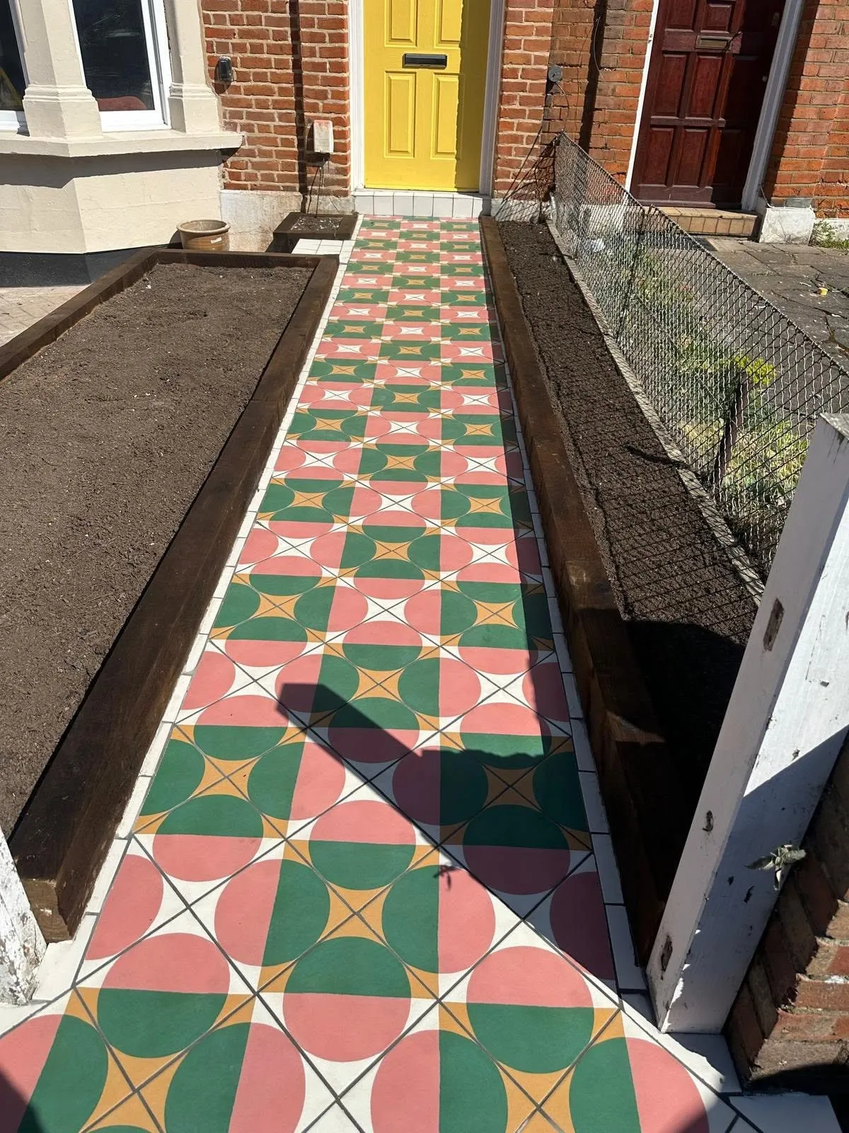 Red and green Victorian tiled front path between two sleeper raised beds